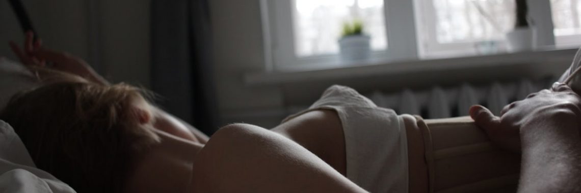 A serene scene of a woman resting in bed bathed in soft morning light.